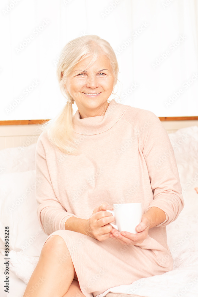 Senior woman sitting on bed with coffee. Senior woman sitting on bed with coffee.
