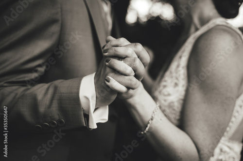 Black and white photo on dancing pair in formal clothes. Close up of holding hands. Shallow depth of field.