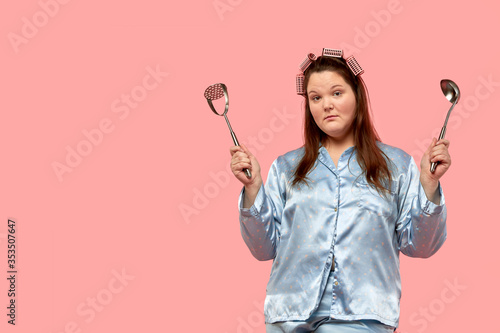 Beautiful fat girl in blue pajamas with kitchen utensils.