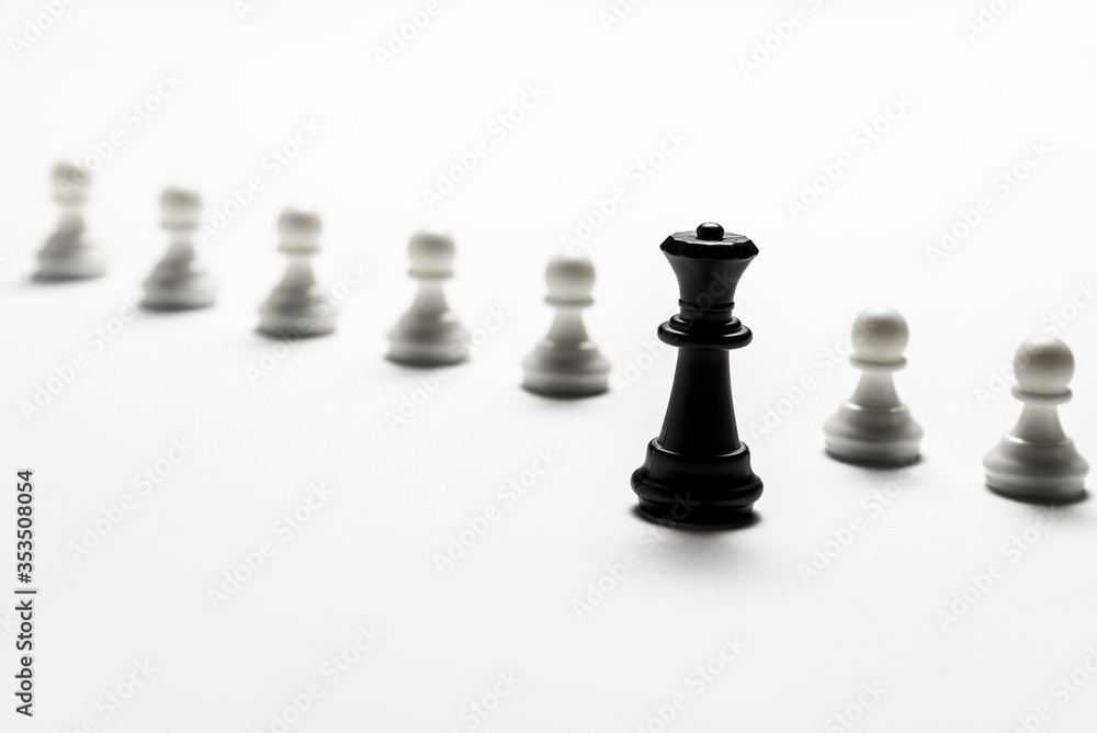 chess black queen stands against white pawns. Symbol of leadership and confrontation. Horizontal frame chess black queen stands against white pawns. Symbol of leadership and confrontation. Horizontal frame