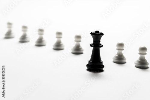 chess black queen stands against white pawns. Symbol of leadership and confrontation. Horizontal frame