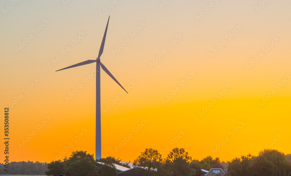 Obraz premium Wind turbine in a yellow sky in sunlight at sunrise in an early spring morning