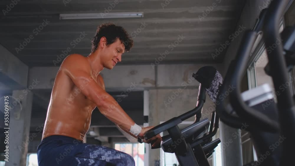 Sport man exercise with cycling machine in gym and he look relax and happy. Concept of good healthy by exercise or workout get strong body to fight virus infection. Sport man exercise with cycling machine in gym and he look relax and happy. Concept of good healthy by exercise or workout get strong body to fight virus infection.