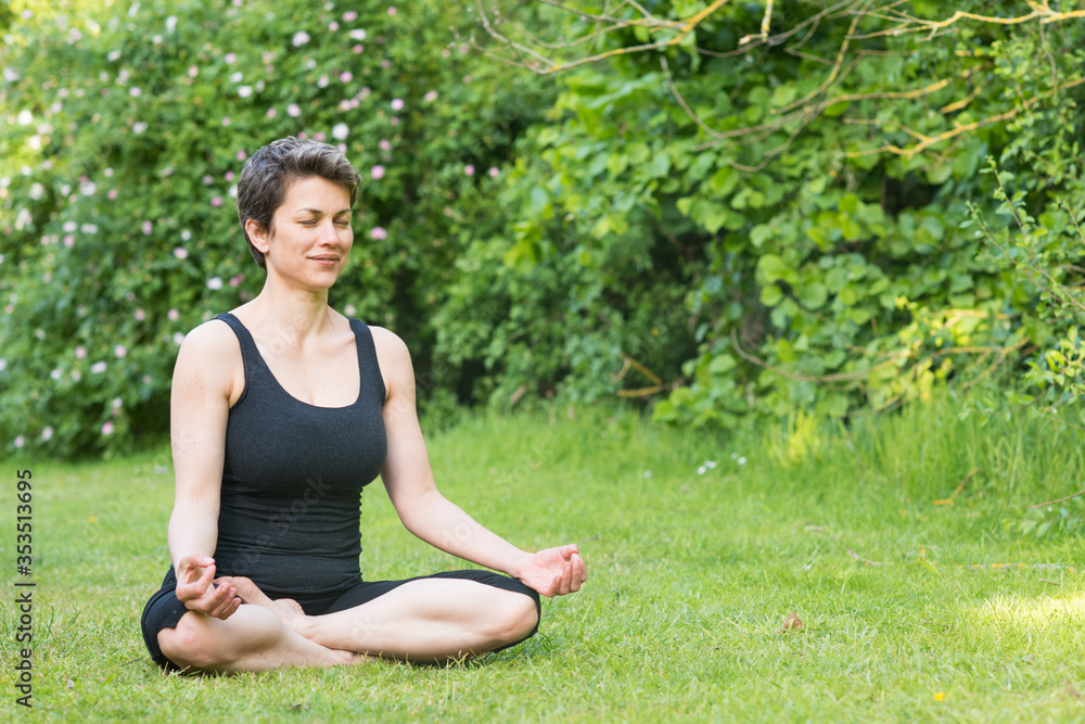 Woman wearing black clothes doing yoga green grass on sunny warm day in park Woman wearing black clothes doing yoga green grass on sunny warm day in park