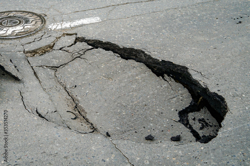 huge pit hole on the road, failure in the asphalt, marked with a tire, dangerous for travel, earthquake, ground movement    