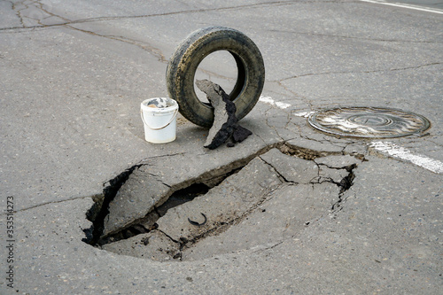 huge pit hole on the road, failure in the asphalt, marked with a tire, dangerous for travel, earthquake, ground movement    