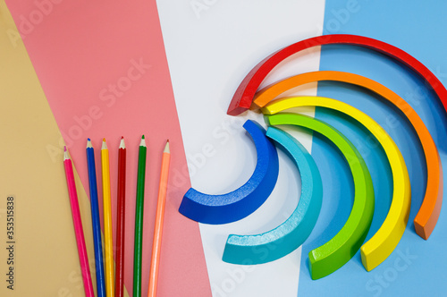 Wooden toy rainbow, arc on pink blue white orange background. Back to school background. Close up. Top view, copy space. Educational games for kindergarten, preschool kids