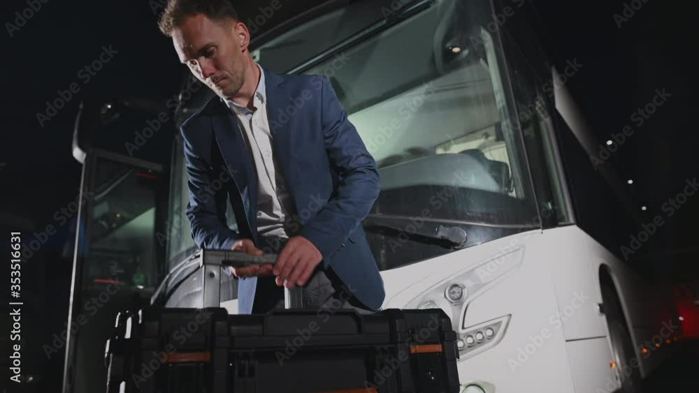 Caucasian International Travel Coach Bus Driver in His 30s with His Equipment Preparing For the Next Trip. Public Transportation Industry. Caucasian International Travel Coach Bus Driver in His 30s with His Equipment Preparing For the Next Trip. Public Transportation Industry.