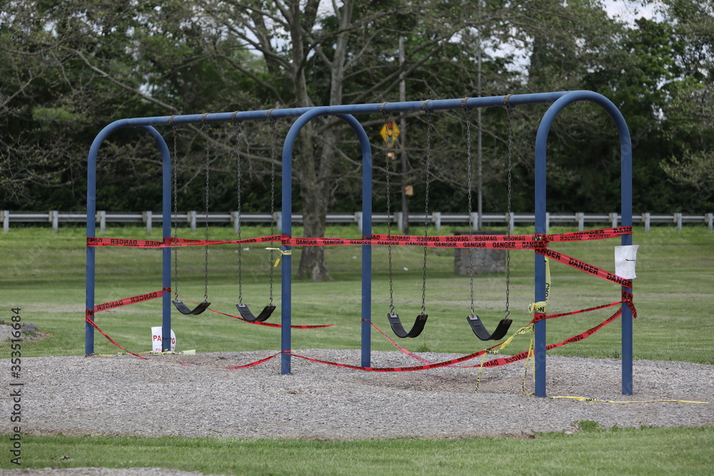 Danger tape is wrapped around playground equipment, indicating the park is closed due to Covid-19 concerns.