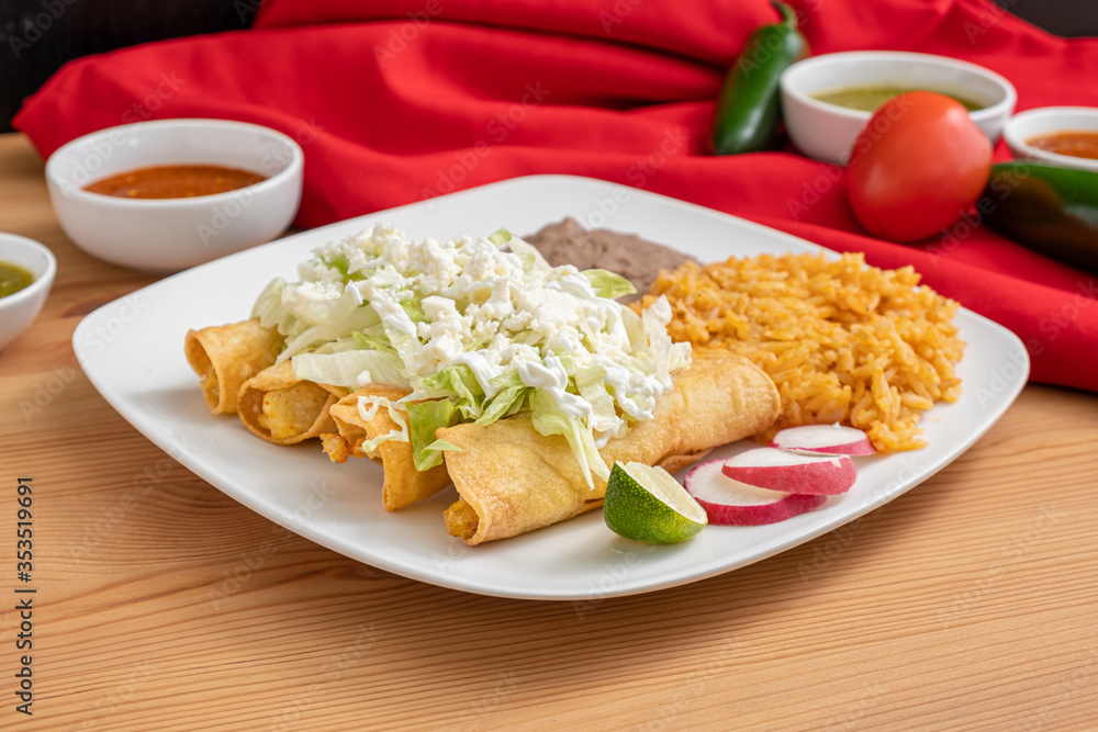 Chicken flautas topped with lettuce, cotija cheese and sour cream