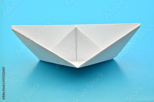 Barco de papel blanco aislado sobre fondo azul © KukiLadrondeGuevara