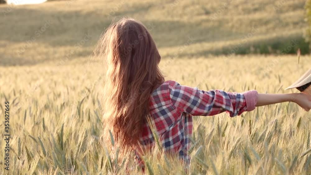 A young woman is touching the grass in a wheat field A young woman is touching the grass in a wheat field