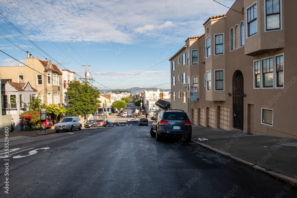 Typical street in San Francisco, California with victorian style houses and cars parked alongside in a sunny December morning