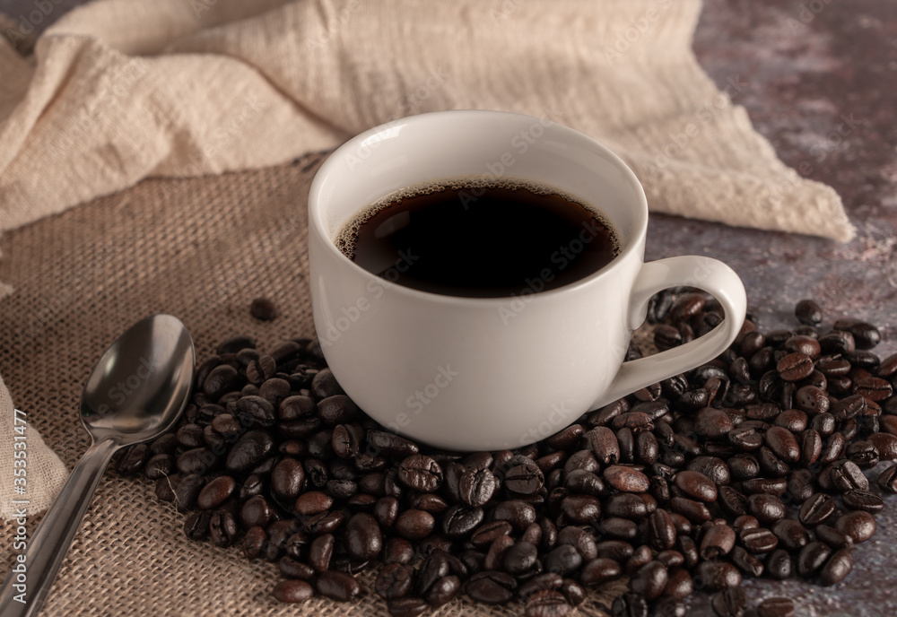 Black Coffee  in White Cup and coffee beans with spoon on table