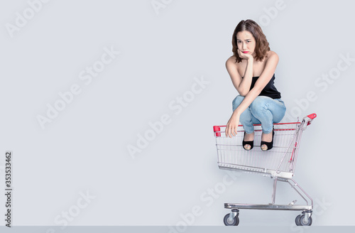 worry face of asian woman waiting to shopping with sitting on empty shopping cart photo