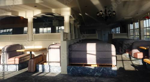Empty abandoned roadside diner restaurant with light shining though windows on booths and tables