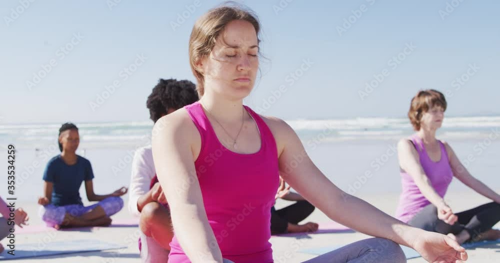 Multi-ethnic group of women doing yoga position on the beach and blue sky background Multi-ethnic group of women doing yoga position on the beach and blue sky background