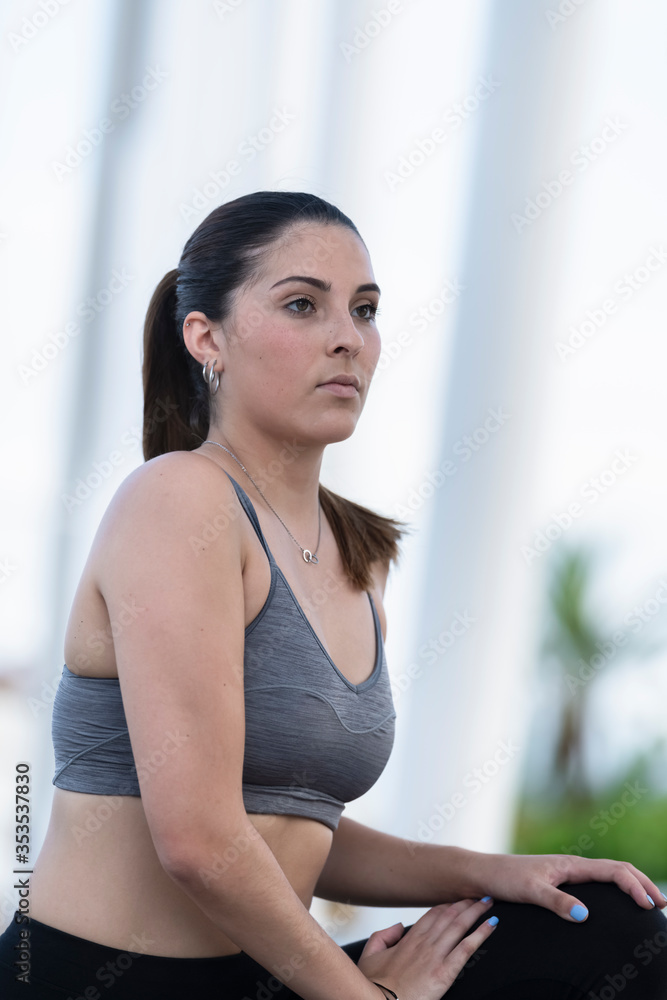 focused young woman wearing sports bra and tights stretching outdoors focused young woman wearing sports bra and tights stretching outdoors