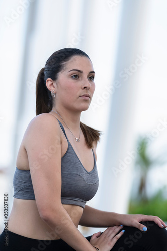 focused young woman wearing sports bra and tights stretching outdoors