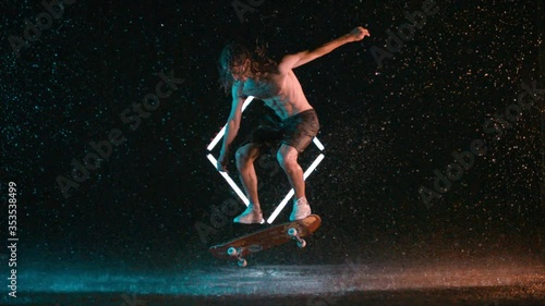 Incredible double kick flip trick by male skateboarder in slow motion rain studio photo