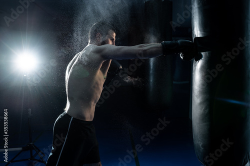 Male boxer hitting a huge punching bag at a boxing studio. man boxer training hard © kalinichenkod