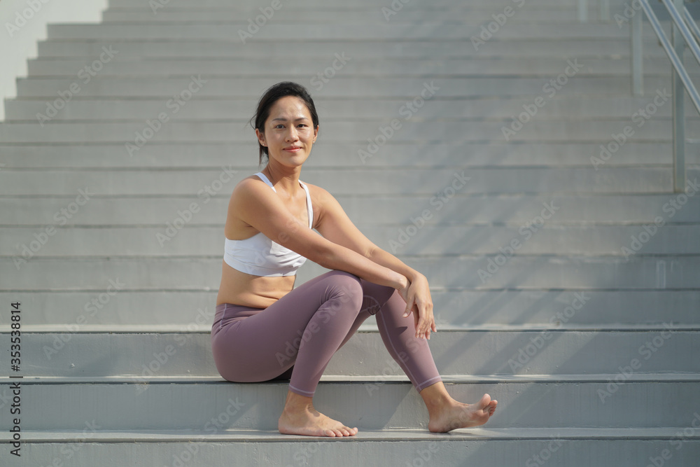 Asian Chinese Woman resting at the stair case in sporting attire