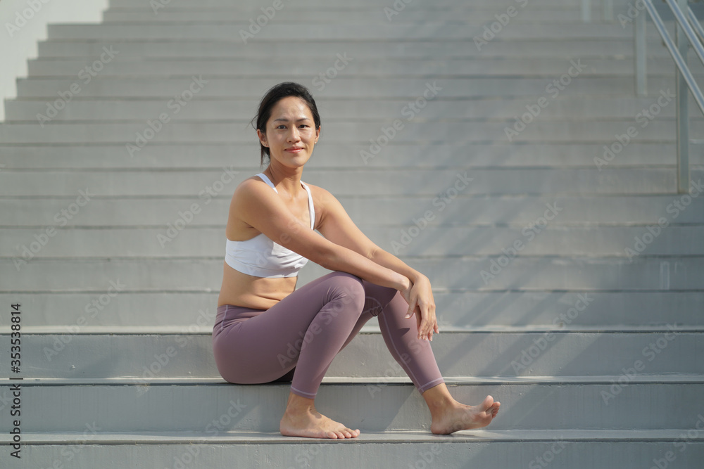 Φωτογραφία Asian Chinese Woman resting at the stair case in sporting attire