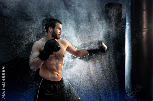 male boxer hitting a huge punching bag at a boxing studio. Man boxer training hard. © kalinichenkod