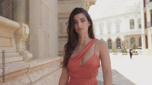 Slow motion tracking of a smiling model in a fusia dress through the old town of Cartagena. photo