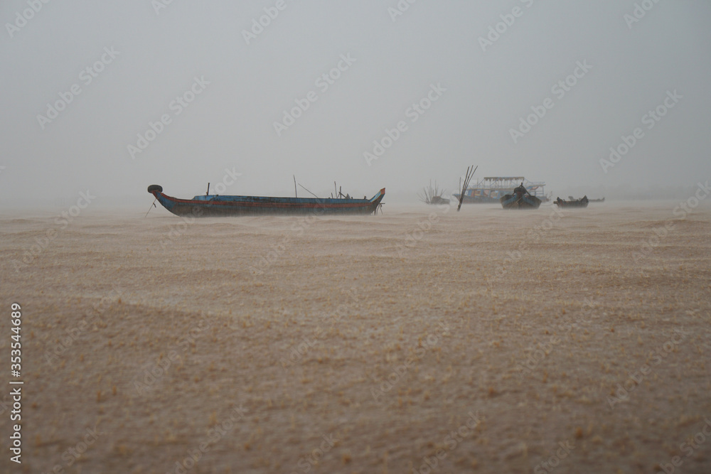 Tonle Sap Lake, Cambodia, fish boats on the waves during a storm, empty ships in the rain, cloudy haze, landscape without people                               