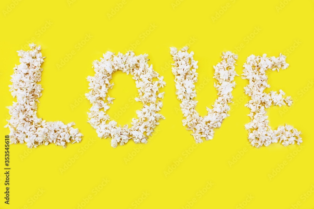 The inscription Love is written in white flowers of lilac on a yellow background. The word love is written with lilac flowers. Flower inscription Love. Background for a greeting card. Wedding, Valenti