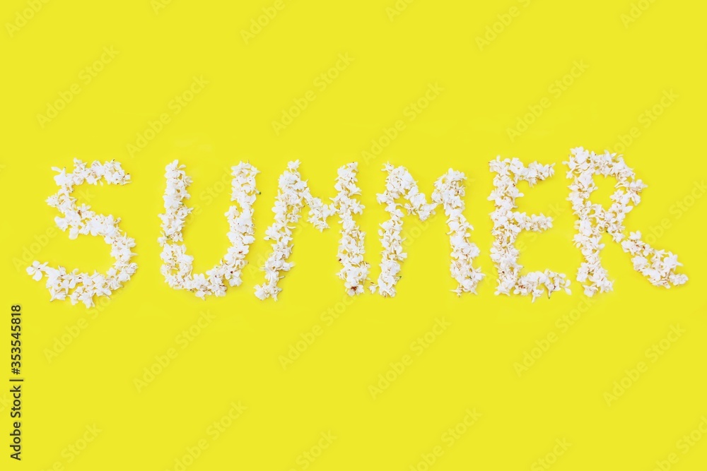 The inscription Summer is written in white flowers of lilac on a yellow background. The word Summer is written with lilac flowers. Flower inscription Summer. Background for a greeting card. Wedding