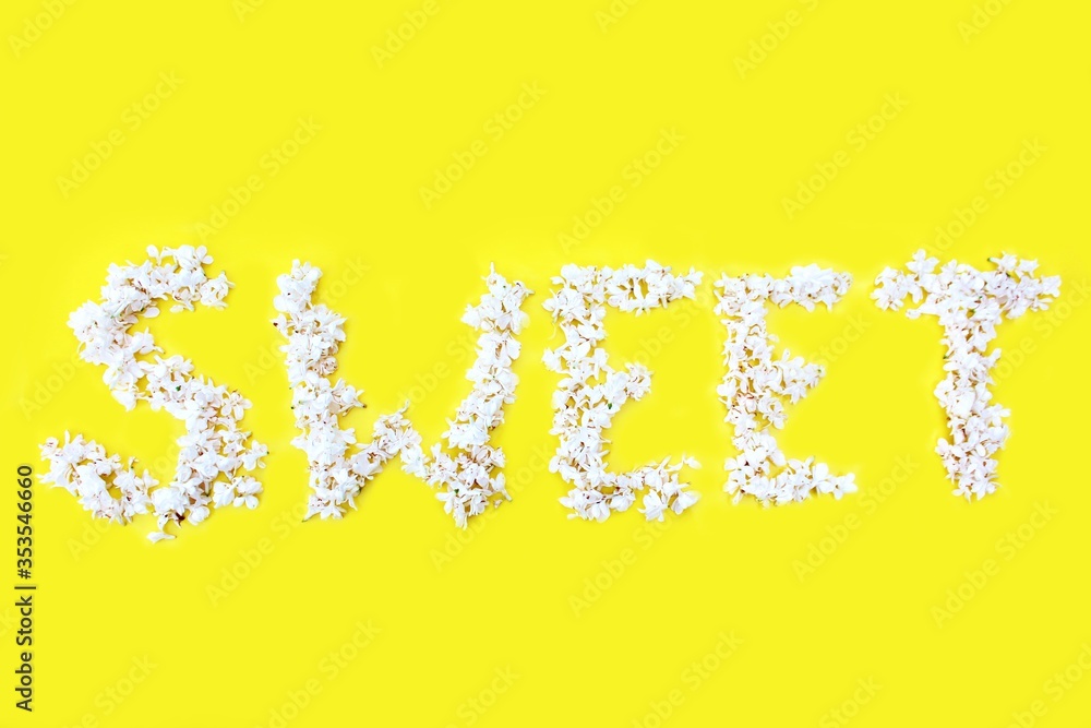 The inscription Sweet is written in white flowers of lilac on a yellow background. The word Sweet is written with lilac flowers. Flower inscription Sweet. Background for a greeting card. Wedding