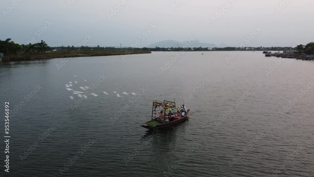 Fantastic view of a wooden boat sailing in the river with flocks of birds flying Fantastic view of a wooden boat sailing in the river with flocks of birds flying