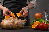 The chef prepares a chicken with fruit for baking for the holiday, Christmas, New Year, on the background of a concrete wall. Background for menu and cooking recipes.