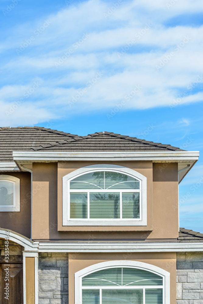 A perfect neighborhood. Houses in suburb at Summer in the north America. Fragment of a luxury house with nice window over blue sky.