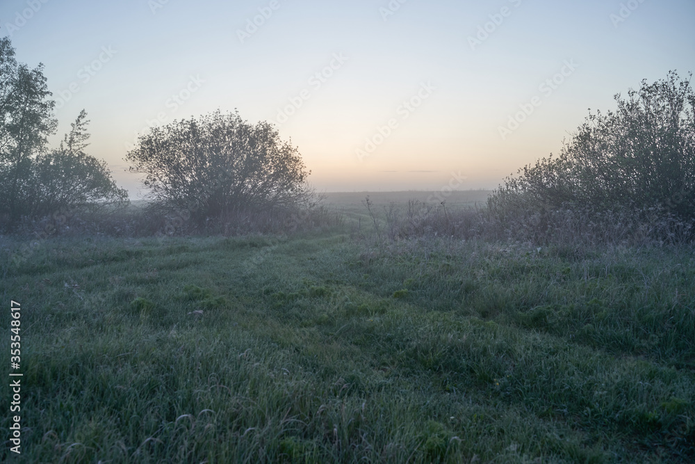 Early spring. Morning dawn over the lake in a misty, thoughtful haze. Beautiful view of the forest covered with fog early in the morning. The sun's rays of light. May. Early spring. Morning dawn over the lake in a misty, thoughtful haze. Beautiful view of the forest covered with fog early in the morning. The sun's rays of light. May.