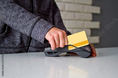 The young man s hands are held by a card on the payment terminal