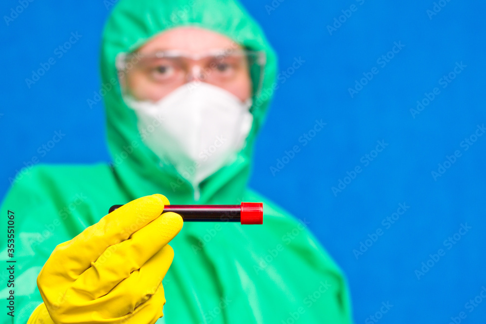 Medical worker in coveralls wearing glasses and rubber gloves with tubes working in the laboratory