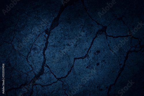 Dark blue grunge background. Navy blue abstract background. Toned concrete wall texture with cracks. Rough cracked stone surface.