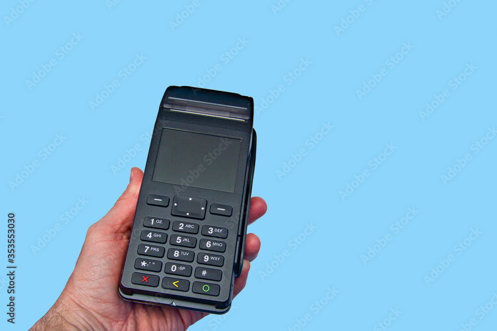 Hand is holding a credit card payment terminal on blue background. Hand is holding a credit card payment terminal on blue background.