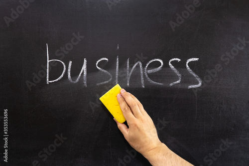 A hand erasing the word BUSINESS from the chalkboard