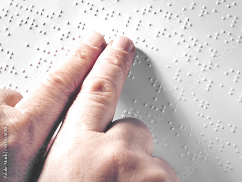 Hands of a blind person reading some braille text touching the relief. Horizontal photo