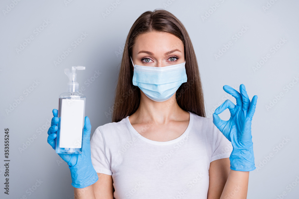 Photo of confident lady hold antiseptic big bottle disinfection safety concept showing okey symbol advising buy use spray wear latex gloves protect face mask isolated grey color background