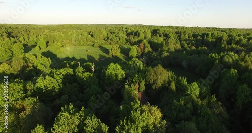 4K early summer sunny afternoon aerial video of abandoned village site with ruins of houses and church inmiddle of dense green wild woods in Russia's Yaroslavl region photo