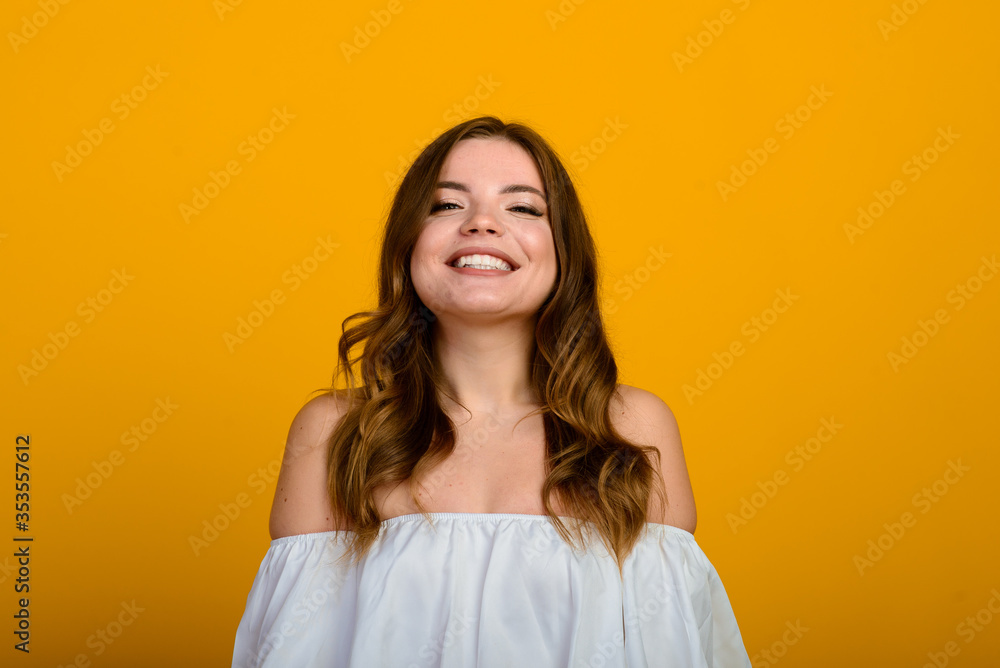 Dark-haired young woman with a smile and big suprised eyes posing on yellow background. Dark-haired young woman with a smile and big suprised eyes posing on yellow background.