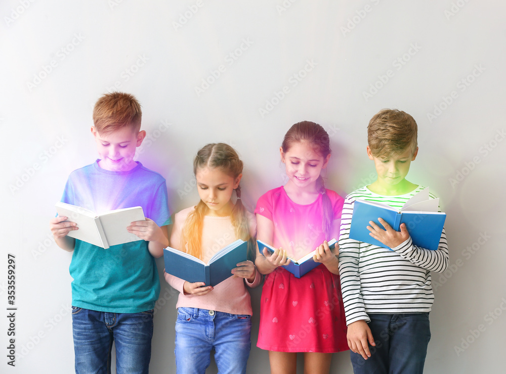 Cute little children reading books on grey background Cute little children reading books on grey background