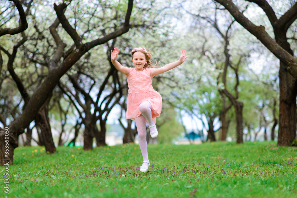 Pretty child girl smiling and playing in flowers of the garden, blooming trees, cherry, apples. Pretty child girl smiling and playing in flowers of the garden, blooming trees, cherry, apples.
