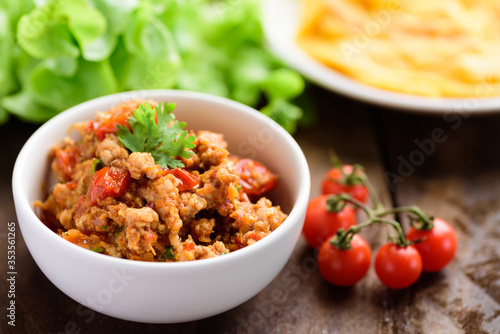 Northern Thai food (Nam Prik Ong), spicy chili minced pork with tomatoes in a bowl on wooden background