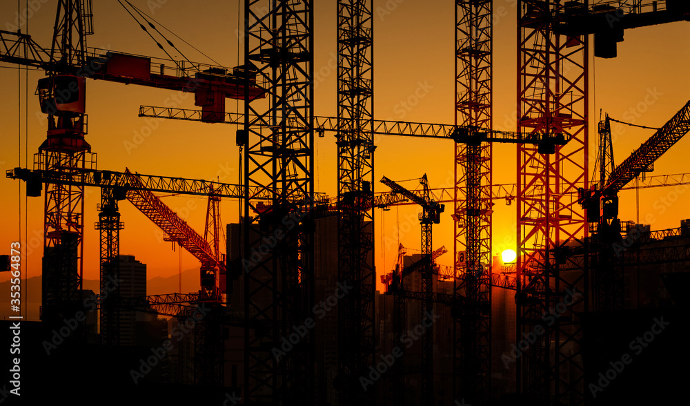 construction site and building cranes on sunset sky in city -